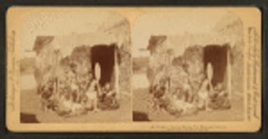 Group of natives eating poi [in front of thatched hut], Hawaiian Islands