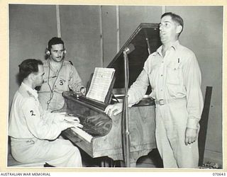 PORT MORESBY, PAPUA, 1944-02-26. SERGEANT K. PLANT, ROYAL AUSTRALIAN AIR FORCE (1), A WELL KNOWN NATIONAL STATION PERFORMER, RENDERS THE FIRST SONG OVER 9PA, THE NEW AUSTRALIAN BROADCASTING ..