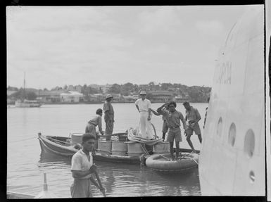 Group of unidentified men in boats alongside Tasman Empire Airways Ltd Short Empire flying boat 'Aotearoa', Suva, Fiji