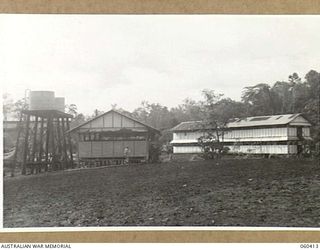 SOGERI, NEW GUINEA. 1943-11-20. BUILDINGS AT THE SCHOOL OF SIGNALS, NEW GUINEA FORCE. THE BUILDING ON THE LEFT IS THE DENTAL SECTION AND THE REGIMENTAL AID POST. THE DOUBLE STORIED BUILDING ON THE ..