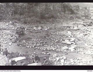 WAU-LABU ROAD, NEW GUINEA, 1945-12-13. AN R4 BULLDOZER OF 8 MECHANICAL EQUIPMENT COMPANY LEVELLING OUT A CROSSING OF MUMENG CREEK WHILE SEVERAL VEHICLES WAIT TO CROSS