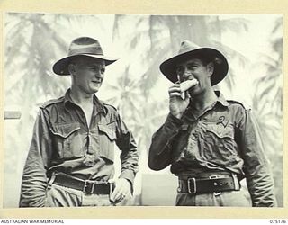 SIAR, NEW GUINEA. 1944-08-09. VX43106 LIEUTENANT R.L. BARTLETT, HEADQUARTERS, 25TH INFANTRY BATTALION (2) SAMPLES A FRESHLY BAKED SAUSAGE ROLL WATCHED BY Q21901 WARRANT OFFICER M. OLSEN, THE UNIT ..