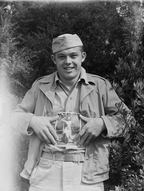 [Portrait of serviceman holding a Tudor Collins photo of a topless Pacific Island woman]