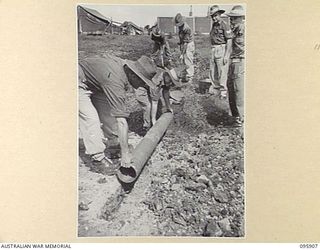 WEWAK POINT, NEW GUINEA. 1945-08-29. A WORKING PARTY FROM 19 INFANTRY BRIGADE TROOPS LAYING PIPES DOWN IN THE MEN'S LINES FOR DRAINAGE