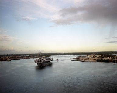 Aerial port bow view of the nuclear-powered aircraft carrier USS ENTERPRISE (CVN 65) as it enters Pearl Harbor. Members of the crew man the rail