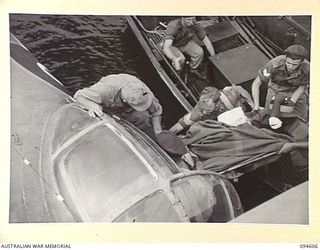 NANTAMBU, NEW BRITAIN, 1945-07-26. AN INJURED NATIVE OF THE NEW GUINEA INFANTRY BATTALION, WHOSE HAND WAS BLOWN OFF, BEING TAKEN ABOARD A ROYAL NEW ZEALAND AIR FORCE CATALINA FLYING-BOAT FOR ..