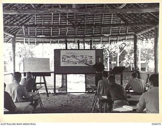 YALU, NEW GUINEA. 1945-08-03. CAPTAIN J.A. SHIMELD, INSTRUCTOR, NEW GUINEA TRAINING SCHOOL, GIVING A LECTURE ON MAP READING