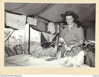 WUNUNG PLANTATION, JACQUINOT BAY, NEW BRITAIN. 1945-03-02. VFX138593 SISTER M. O'LOUGHLIN (2) ATTENDING TO THE DRESSINGS OF N464401 PRIVATE E.R. HODGSON, 19TH INFANTRY BATTALION IN THE SURGICAL ..