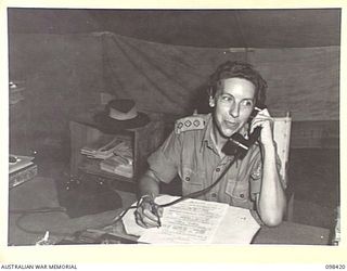 RABAUL, NEW BRITAIN. 1945-10-31. CAPTAIN H.C. WITT, OFFICER COMMANDING AUSTRALIAN ARMY MEDICAL WOMEN'S SERVICE, OF 118 GENERAL HOSPITAL AT HER DESK, IN TEMPORARILY ERECTED TENT ACCOMMODATION