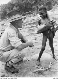 TOROKINA, BOUGAINVILLE ISLAND, SOLOMON ISLANDS. C. 1945-02. 42933 CORPORAL R. TROTTER, COBDEN, VIC, MAKES FRIENDS WITH A TINY NATIVE CHILD IN THE TOROKINA AREA