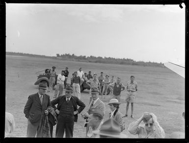 View of unidentified passengers in front of a transport plane with locals and military personnel looking on at [Fua'Amotu?] Airfield, Tonga