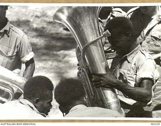 SOUTHPORT, QLD. 1944-01-18. A NEW GUINEA POLICE BOY ADMIRING THE EUPHONIUM OF A MEMBER OF THE BAND OF THE 4TH ARMOURED BRIGADE