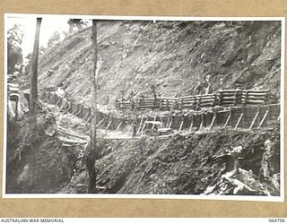 WAU, NEW GUINEA. 1944-02-11. NEW GUINEA NATIVES, SUPERVISED BY ENGINEERS OF THE 2/4TH FIELD SQUADRON, ROYAL AUSTRALIAN ENGINEERS, BUILDING LOG RETAINING WALLS ON AN EARTH SLIDE TO PROTECT THE NEW ..