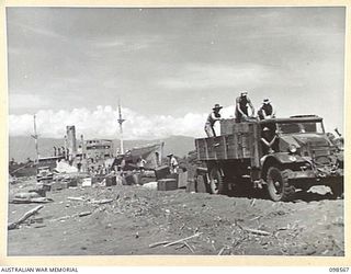 MALAHANG BEACH, LAE, NEW GUINEA. 1945-10-16. TROOPS OF FIRST ARMY DESTROYED SURPLUS AMMUNITION AT MALAHANG BEACH. THEY ARE SHOWN EMPTYING CORDITE FROM CHARGE. THE WRECK OF THE JAPANESE VESSEL, ..