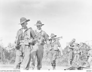 BABIANG, NEW GUINEA. 1944-11-07. MEMBERS OF C TROOP, 2/10 COMMANDO SQUADRON, LOADED WITH BATTLE GEAR COMPRISING WEAPONS, MOSQUITO NET, GROUND SHEETS AND HAVERSACK LEADING THEIR WAY OVER THE ..