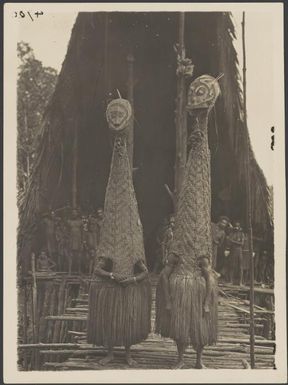 Masked dancers in front of the men's longhouse at Tovei village, Urama Island, Gulf Province, Papua New Guinea, June 1921 / Frank Hurley