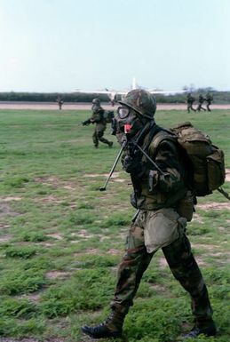 Marines of Company A, Battalion Landing Team 1/3, wearing Nuclear, Biological, Chemical (NBC) protective masks, move forward during a mock assault. They are participating in Operation KERNAL BLITZ