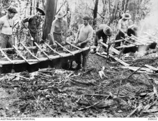 FARIA VALLEY, NEW GUINEA. 1943-10-17. COOKS OF THE 2/16TH AUSTRALIAN INFANTRY BATTALION COOKING FOR MORE THAN 600 MEN IN THE OUTDOORS NEAR JOHN'S KNOLL. LEFT TO RIGHT: QX32042 ACTING CORPORAL J. ..