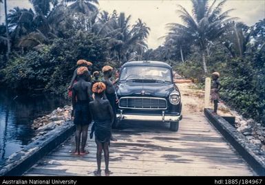 Car and Papua New Guineans on wooden bridge