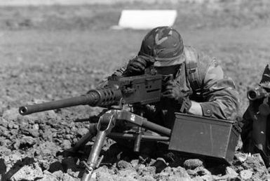 A member of 1ST Battalion, 3rd Marines, adjusts the rear sight of an M-2 .50-caliber machine gun mounted on a tripod