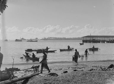 [View of a shoreline with many canoes and boats in the sea]