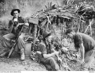 FARIA RIVER AREA, NEW GUINEA. 1943-11-07. ON THE WAY TO THE FORWARD AREA A COMPANY OF THE 2/27TH AUSTRALIAN INFANTRY BATTALION IS PROVIDED WITH CUPS OF TEA AT THE HALFWAY STAGGER INN. SHOWN ARE, ..