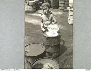 MILNE BAY, NEW GUINEA. 1944-04-04. S111887 PRIVATE S.G.R. FREEMAN (1), AT THE 2ND AUSTRALIAN BULK PETROLEUM STORAGE COMPANY STENCILLING THE TYPE OF FUEL CONTENTS ON 44 GALLON DRUMS