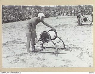 TOROKINA, BOUGAINVILLE, 1945-07-08. PRIVATE E. MEEK, 61 TRANSPORT COMPANY (1) REELING OUT THE LINE IN THE RESCUE DISPLAY DURING THE CHAMPIONSHIP SURF CARNIVAL HELD BY SOLOMON ISLAND SURF LIFE ..