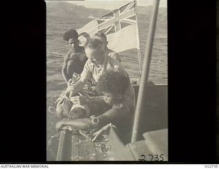 PORT MORESBY, PAPUA. C. 1944. A CASUALTY IN A STOKES LITTER BEING PUT ABOARD A MOTOR LAUNCH OF THE RAAF RESCUE SERVICE WITH THE HELP OF TWO PAPUAN NATIVE CREW MEMBERS