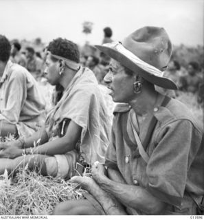 1942-11-19. NEW GUINEA. KOKODA. NATIVE CARRIERS OR PORTERS HAVE PLAYED A BIG PART IN THE ALLIED ADVANCE IN NEW GUINEA. NATIVE CARRIERS AT KOKODA LISTEN TO A SPEECH OF CONGRATULATIONS BY A HIGH ..