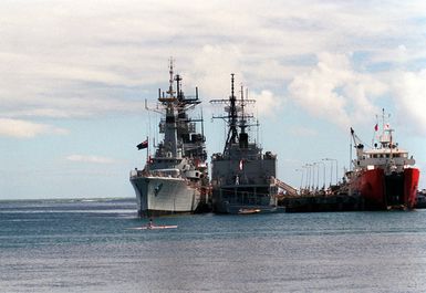 A stern view of the French light transport ship FS DUMONT D'URVILLE (L-9032) and the New Zealand frigate HMNZS WELLINGTON (F-69) moored side by side at a pier