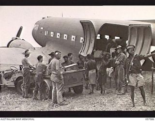 KAIAPIT, NEW GUINEA. 1943-09-24. SUPPLIES ARRIVE AT THE AIRSTRIP FOR HQ 21ST AUSTRALIAN INFANTRY BRIGADE. NATIVES UNLOAD FROM THE AIRCRAFT INTO A TRAILER