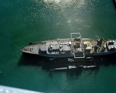 An aerial port view of the submarine tender USS PROTEUS (AS 19) with two submarines moored alongside