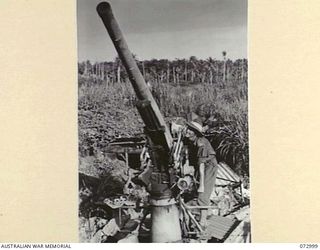 MADANG, NEW GUINEA. 1944-04-25. AN AUSTRALIAN LIEUTENANT MANIPULATES THE VERTICAL TRAVERSE OF A BOMB DAMAGED 75MM JAPANESE FIELD ANTI-AIRCRAFT GUN. THIS GUN WAS MOBILE AND WAS USED EXTENSIVELY ..