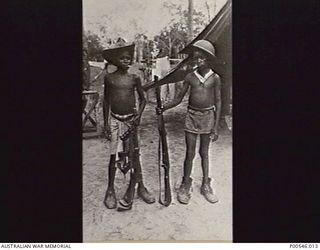 NEW GUINEA. 1945? TWO NATIVE CHILDREN DRESSED AS SOLDIERS, SMOKING CIGARETTES AND HOLDING RIFLES. (DONOR D. HAMMOND)