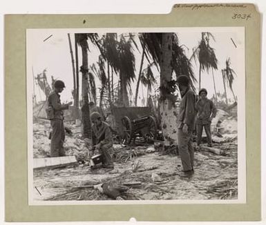 Photograph of Coast Guardsmen at Tarawa Pausing for a Look at a Japanese Field Gun