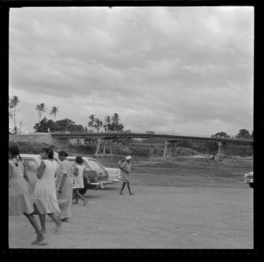 Indians in carpark beside a stream and bridge, Nadi, Fiji