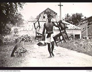 NAURU ISLAND. 1945-09-14. A NAURUAN NATIVE WITH EQUIPMENT WHICH HE HAS SOUVENIRED FROM THE JAPANESE ARMY HEADQUARTERS SOON AFTER PERSONNEL OF THE 31/51ST INFANTRY BATTALION OCCUPIED THE ISLAND