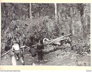 BERRY'S HILL, CENTRAL BOUGAINVILLE. 1945-06-27. NATIVE STRETCHER BEARERS CARRYING V64795 PRIVATE J. P. SPORN, 7TH BATTALION AMF, DOWN BARGES HILL IN THE DOIABI RIVER AREA. PRIVATE SPORN WAS WOUNDED ..