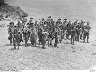 KANOMI BEACH, NEW GUINEA. 1944-01-05. GROUP PORTRAIT OF PERSONNEL OF THE 2/23RD AUSTRALIAN INFANTRY BATTALION 26TH AUSTRALIAN INFANTRY BRIGADE, 9TH AUSTRALIAN DIVISION WAITING TO BOARD BARGES FOR ..