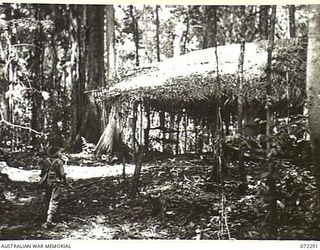 YAULA, NEW GUINEA. 1944-04-10. A MEMBER OF THE 57/60TH INFANTRY BATTALION APPROACHING WHICH HAD FORMERLY BEEN USED AS A JAPANESE HEADQUARTERS