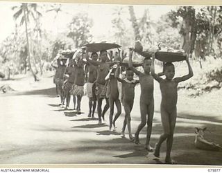 MANAM ISLAND, NEW GUINEA. 1944-09-03. NATIVE WOMEN AND CHILDREN BRINGING FRUIT AND VEGETABLES DOWN TO THE ISLAND BEACH TO TRADE THEM FOR BULLY BEEF AND BISCUITS WITH THE CREW OF THE MEDICAL LAUNCH. ..