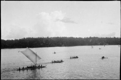 Canoe with a single sail, following several paddled canoes, Lorengau, Manus Island, New Guinea, 1935 / Sarah Chinnery