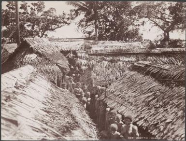 Villagers in alleys between the buildings of Ferasiboa, Malaita, Solomon Islands, 1906 / J.W. Beattie