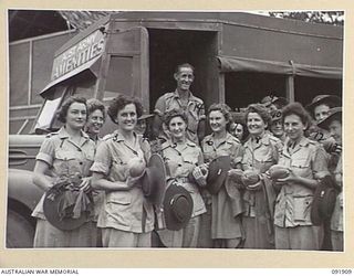 LAE, NEW GUINEA, 1945-05-18. DRIVER E.G. GIBSON (14), WITH A GROUP OF AUSTRALIAN WOMEN'S ARMY SERVICE PERSONNEL OUTSIDE THE AUSTRALIAN WOMEN'S ARMY SERVICE BARRACKS AFTER THEIR RETURN FROM A TRIP ..