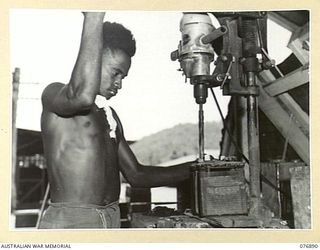 LAE, NEW GUINEA. 1944-11-15. AN AUSTRALIAN NEW GUINEA ADMINISTRATIVE UNIT NATIVE DRILLING LEAD STRAPS FROM STORAGE BATTERY PLATES IN THE BATTERY RECONDITIONING WORKSHOP, 2/7TH ADVANCED WORKSHOP