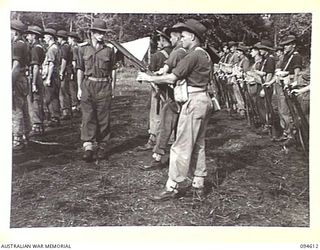 LAMARIEN, HENRY REID BAY, NEW BRITAIN, 1945-07-28. LIEUTENANT R.K. PALMER, TROOP LEADER, HEADQUARTERS TROOP, 2/2 COMMANDO SQUADRON (1), INSPECTING THE WEAPONS OF HIS MEN DURING A PARADE