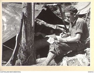 BOUGAINVILLE, 1945-07-14. LIEUTENANT J.W. SINCLAIR, D COMPANY, 15 INFANTRY BATTALION, WHO WAS LATER KILLED IN ACTION, WRITING OUT HIS PATROL REPORT OUTSIDE HIS TWO-MAN TENT IN THE COMPANY ..