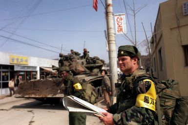 Major (MAJ) Edward R. Cruickshank, Commander of the 1ST Battalion, 299th Infantry, Hawaii Army National Guard, observes the entry of 25th Infantry Division Orange Forces into the city, as they advance against the Blue Forces during the joint South Korean/US Exercise TEAM SPIRIT '84. Visible to the left is an M728 combat engineer vehicle