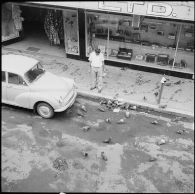 Fijian man feeding pigeons on the street, Fiji, November 1969 / Michael Terry